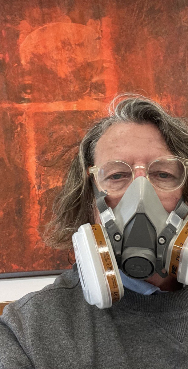 CFJ König wearing a respirator mask at work in his studio, in front of one of his works